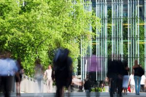 Blurred image of people walking outside a high rise building