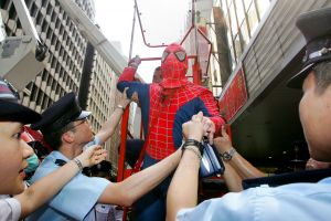 Police officers escort man dressed as Spiderman away after he installed banner in front of big screen in central Hong Kong.