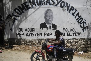 A moto-taxi driver rides past a mural featuring slain Haitian President Jovenel Moise.