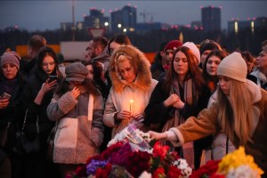 eople lay flowers and light candles next to the Crocus City Hall concert venue in Moscow
