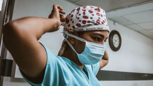 A health worker prepares for a procedure with a mask for COVID-19