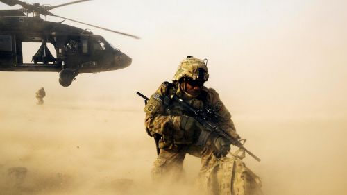 A U.S. soldier shields himself from the rotor wash of a UH-60 Blackhawk helicopter in Afghanistan