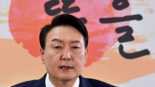  South Korea's president-elect Yoon Suk-yeol speaks during a news conference in front of a peach background with writing.