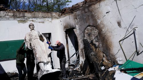 Ukrainians remove the statue of Hryhoriy Skovoroda after a Russian bombing hit the museum.
