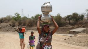 An Indian woman and her children carry water in containers.