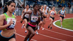 Women running in an international track meet, France.