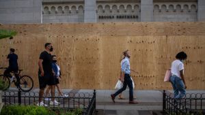 Shoppers walk past a boarded-up Brooks Brothers store on North Michigan Avenue in Chicago on Sept. 4, 2020.
