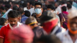 A man wearing a protective mask is seen among people at a crowded market amidst the spread of the coronavirus disease in Mumbai, India
