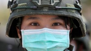 A person wearing a surgical face mask and a military helment.