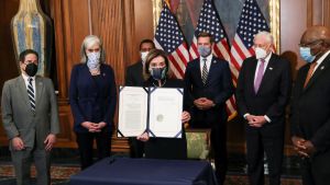 Politicians wearing surgical masks stand with impeachment documents