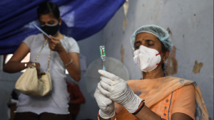 A nurse prepares COVID-19 vaccine for a patient in India