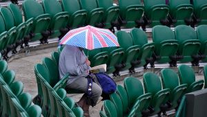 A spectator shelters under an umbrella at the Wimbledon Tennis Championships in London