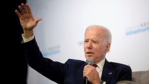 Joe Biden raising his hand while speaking into a microphone