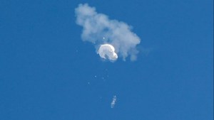 White Chinese balloon is shot down against a blue sky, white smoke. 