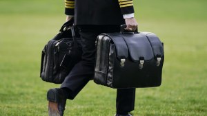 A military aide carries the "President's emergency satchel," also known as "the football," which contains nuclear launch codes