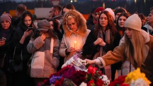 People lay flowers and light candles next to the Crocus City Hall concert venue in Moscow