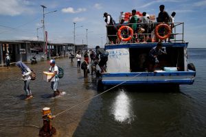 Passengers of a boat walk through rising sea water during high tide at Kali Adem port in Jakarta, Indonesia.