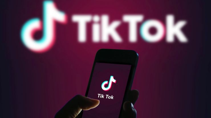 An image of a wall and phone with "TikTok" written on them. 