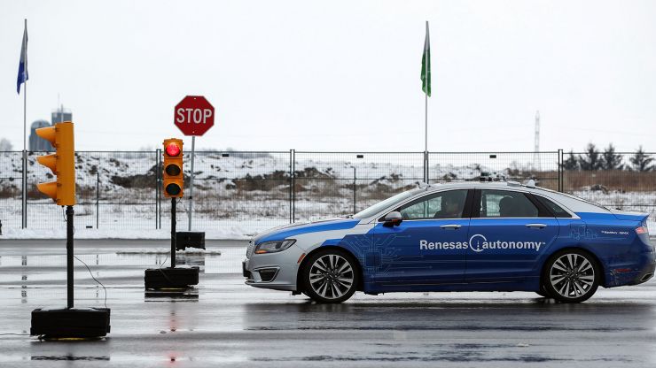 A Renesas electric car is test driven on a track with wet pavement