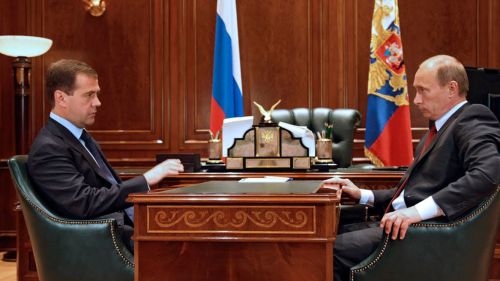 Putin sits at a desk. 