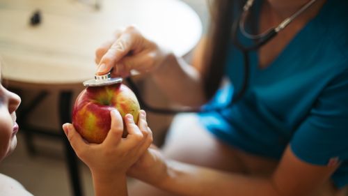 Stethoscope on an apple a child is holding. 