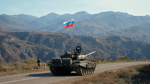 A service member of the Russian peacekeeping troops walks near a tank in Nagorno-Karabakh