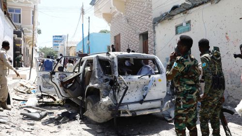 Soldiers stand near a bombed car in Mogadishu, Somalia. 