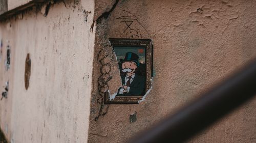 Unsplash - stucco wall with monopoly man illustration breaking through.