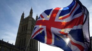 A Union Jack flag waving in front of British Parliament.