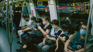 People in masks sit on a subway train