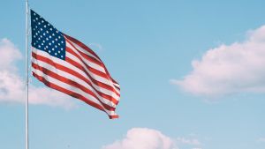 An American flag waving in front of a blue sky with clouds