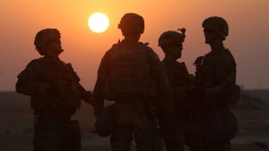 American soldiers at US army base, in front of a sun set.