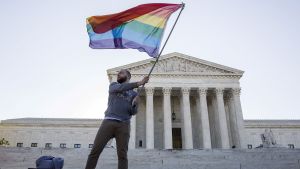 A person waves the gay rights flag in front of the Supreme Court