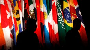 Silhouettes of people stand in front of multi-national flags
