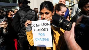 A person holds up a sign saying "90 million reasons for change" outside the Google offices