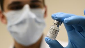Army Spc. Angel Laureano holds a vial of the COVID-19 vaccine, Walter Reed National Military Medical Center