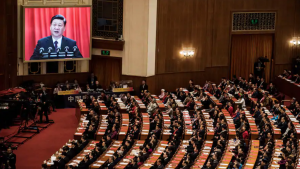 Delegates listen to a speech by Chinese President Xi Jinping as he is seen on a large screen during the National People's Congress