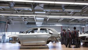 Workers inside an Audi plant in Mexico, with the frame of a car in the foreground