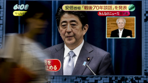 A woman walks past a television screen showing Prime Minister Shinzo Abe in Tokyo, 2015.
