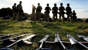 Weapons lie on the ground as Ukrainian personnel take a break during training